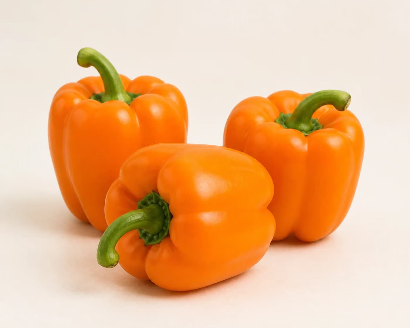 Fresh Orange Capsicum arranged on a warm off-white surface.