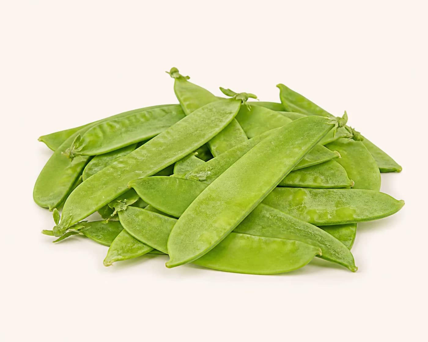 Fresh Snow Peas arranged on a warm off-white surface.