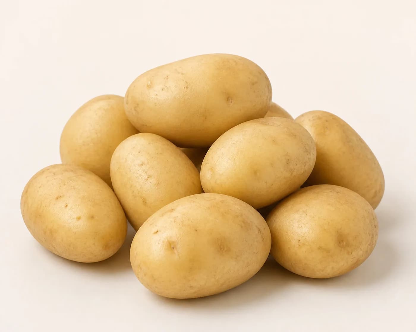 Fresh Kufri Jyoti Potato arranged on a warm off-white surface.