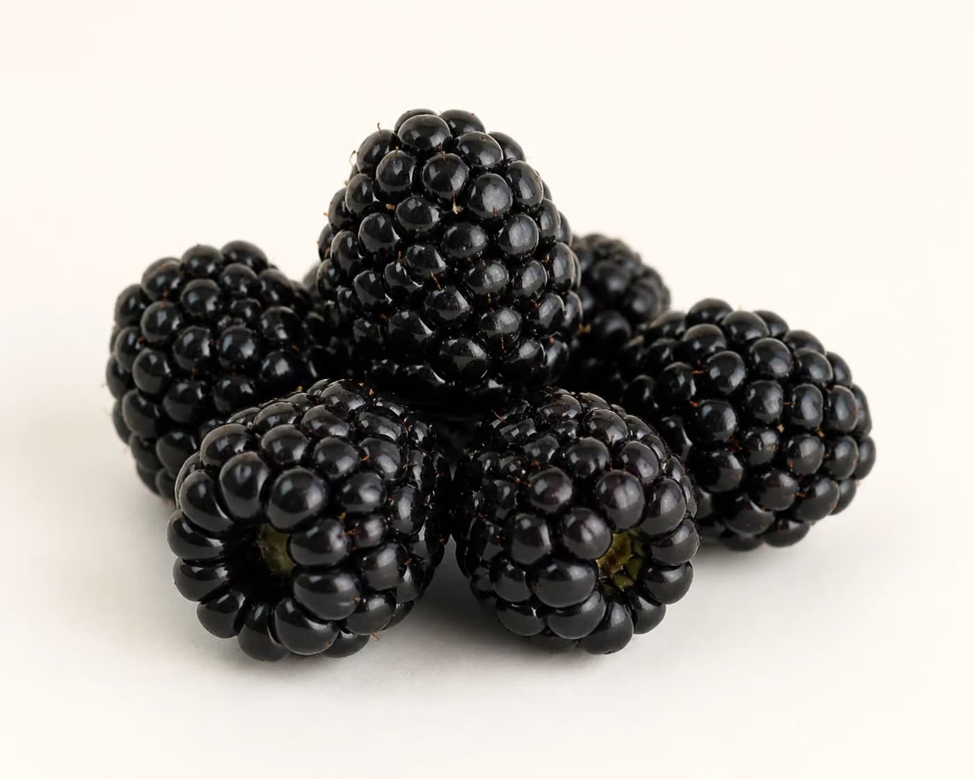 Fresh Blackberry arranged on a warm off-white surface.