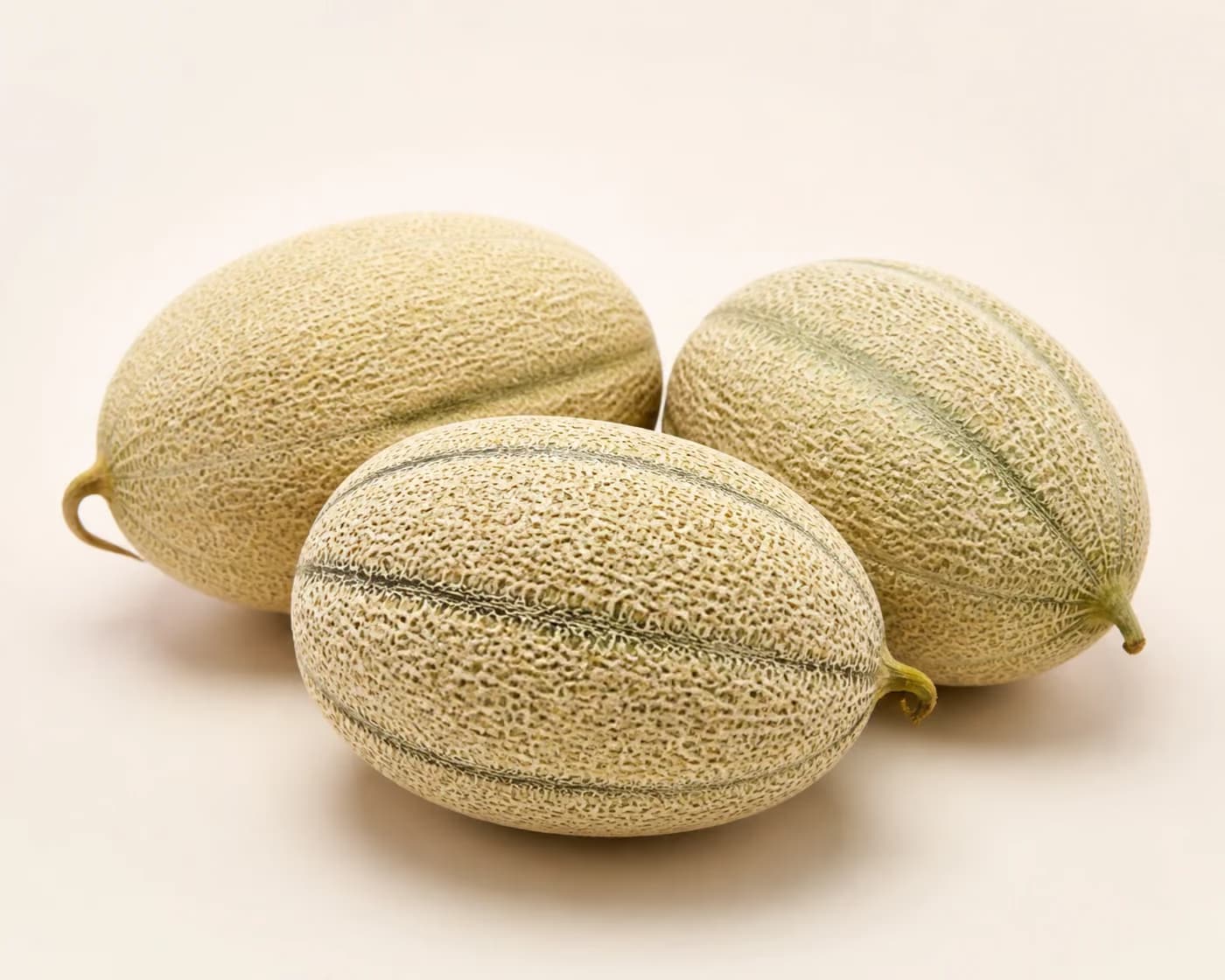 Fresh Hami Melon arranged on a warm off-white surface.