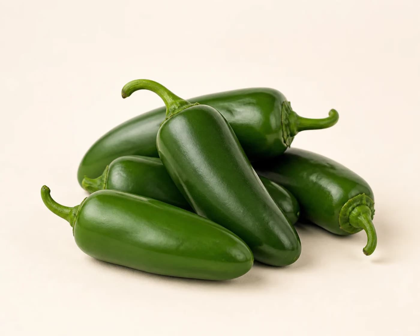 Fresh Jalapeño arranged on a warm off-white surface.