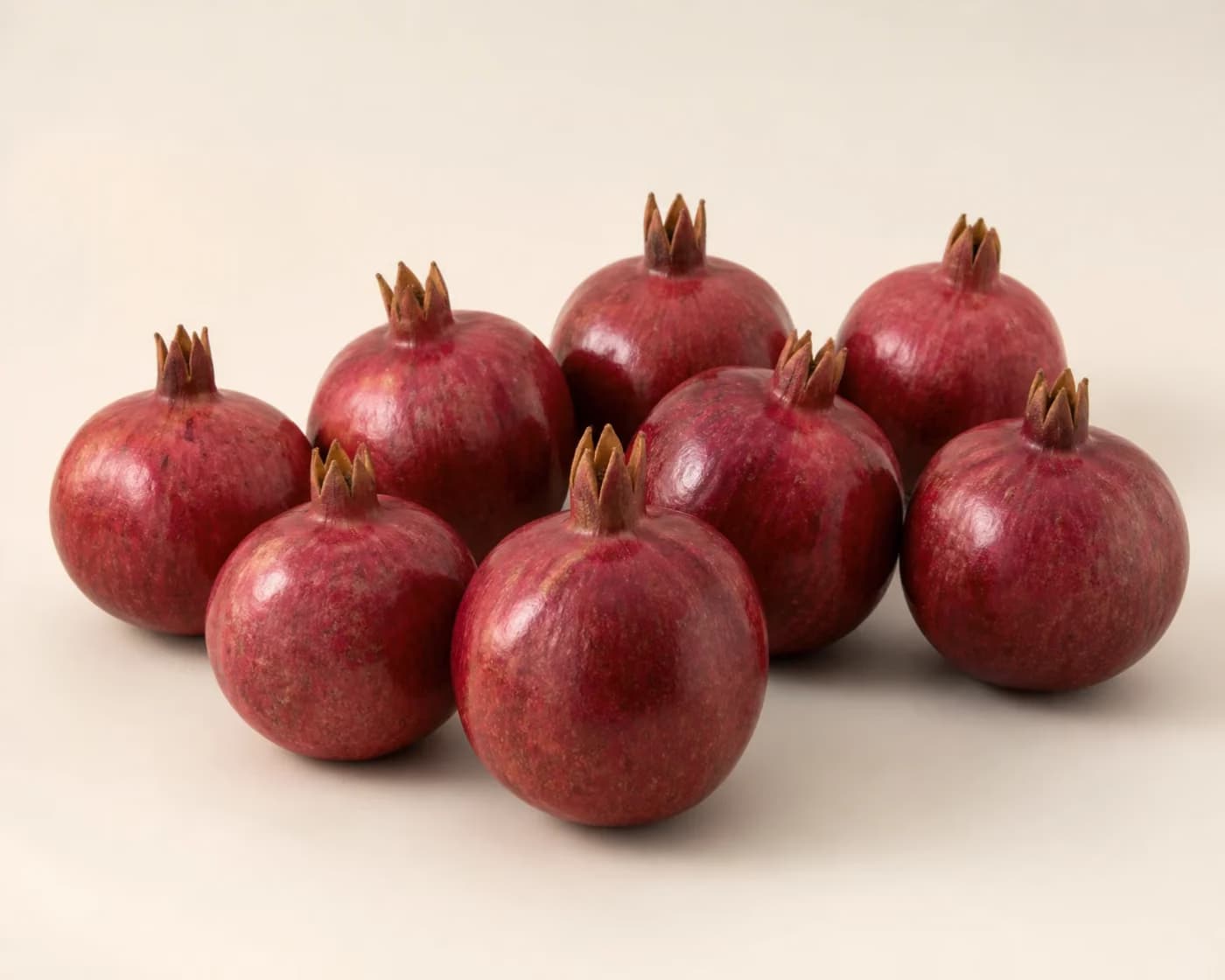 Fresh Kandhari Pomegranate arranged on a warm off-white surface.