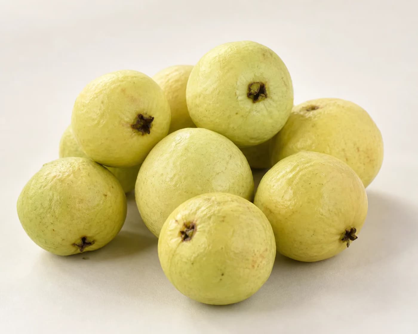 Fresh Allahabad Safeda Guava arranged on a warm off-white surface.