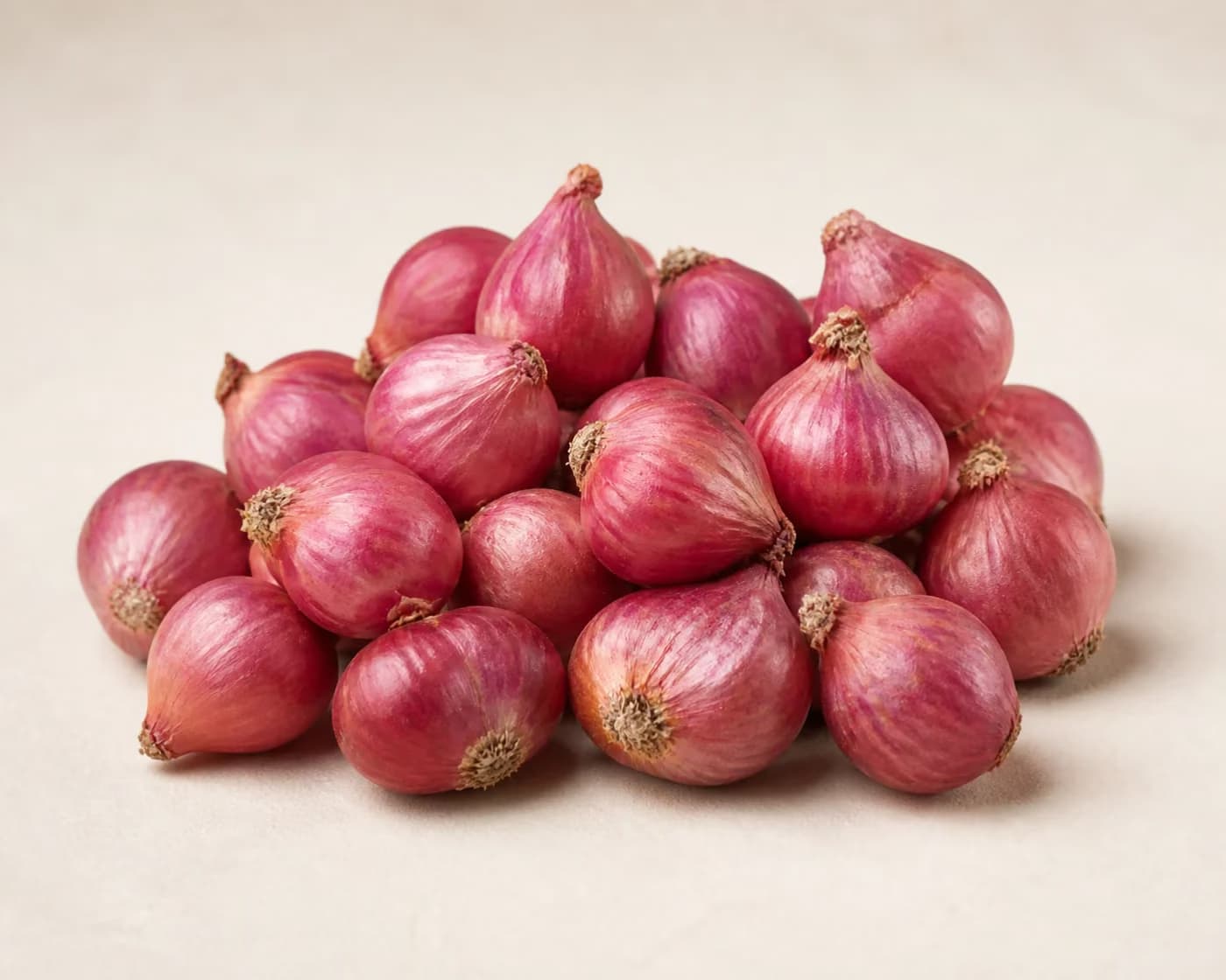 Fresh Sambar Onion arranged on a warm off-white surface.