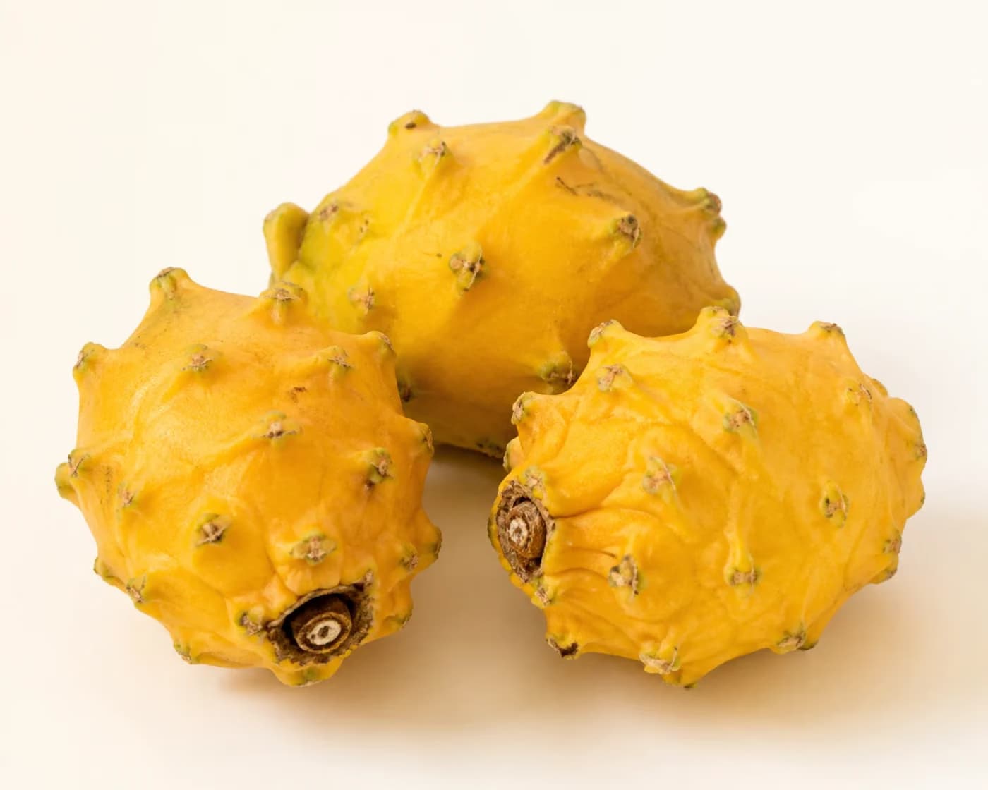 Fresh Yellow Dragon Fruit arranged on a warm off-white surface.